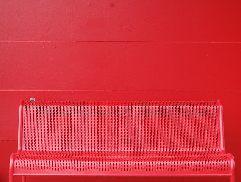 Red bench in front of a red wall.