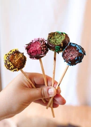 Hand holding four colourful chocolate cake pops.