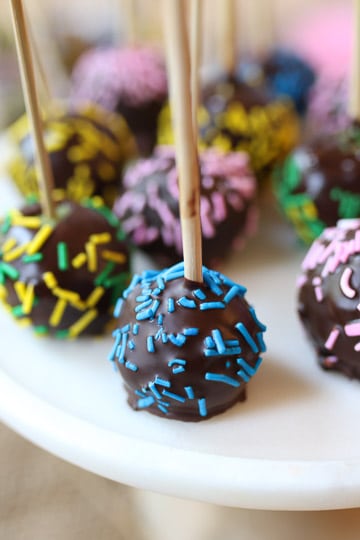 Birthday cake pops served on a white plate.