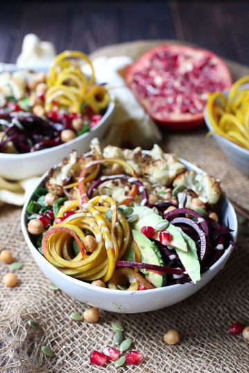 vegan tahini beet power bowl in a white bowl garnished with pomegranate seeds