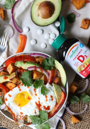 birds eye view of a nourish bowl topped with an egg next to a bottle of vitamin D supplements