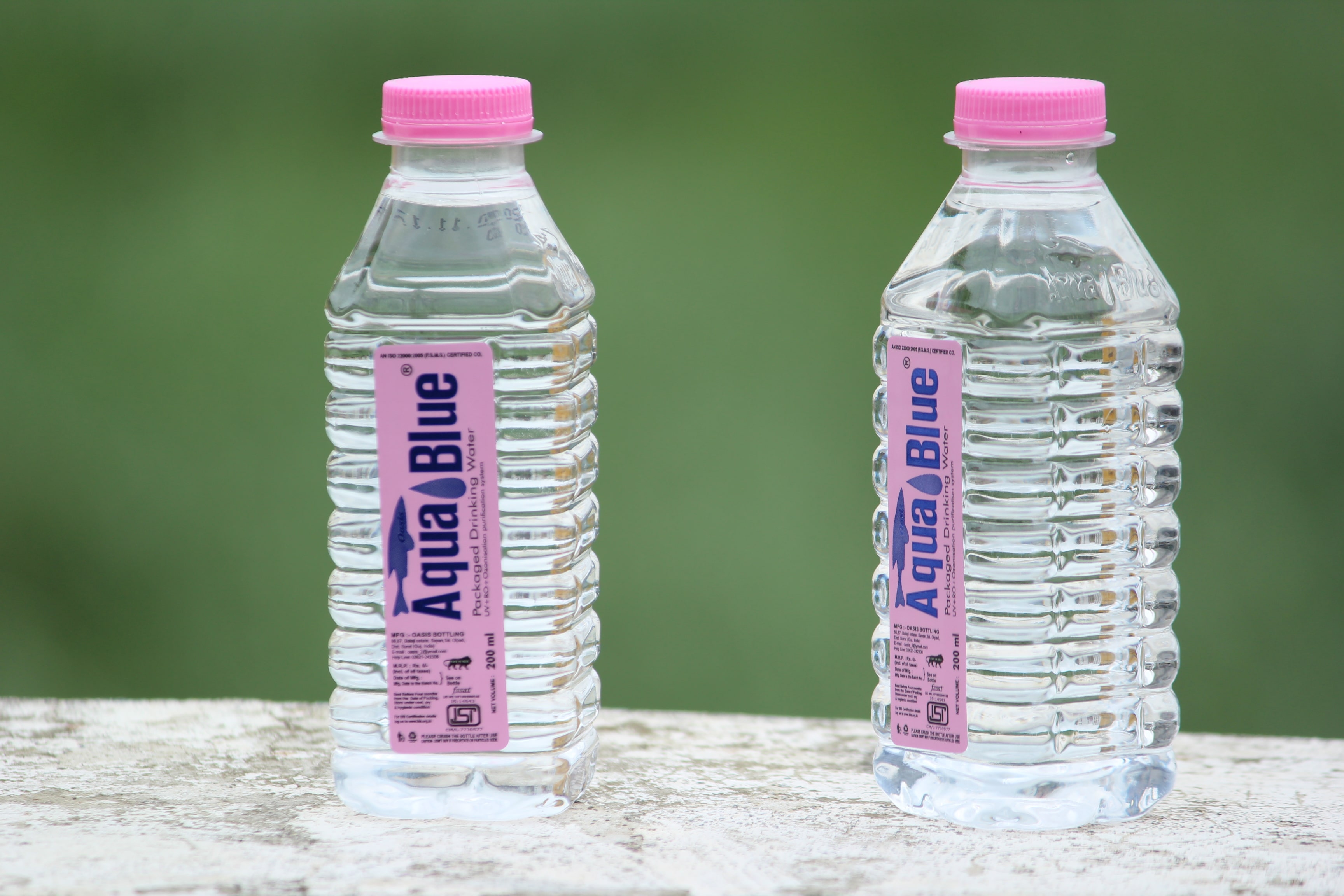 A two plastic water bottles with pink labels and lids.