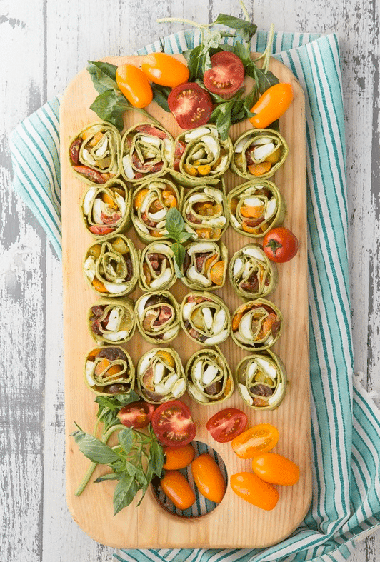 Pinwheel sandwiches served on a wooden board. 