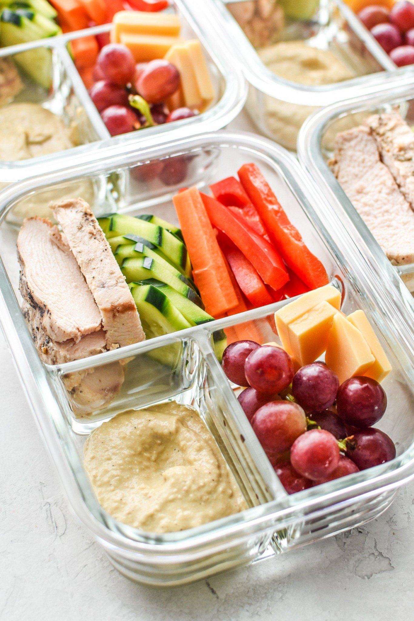 Chicken and veggies with hummus in lunch boxes.