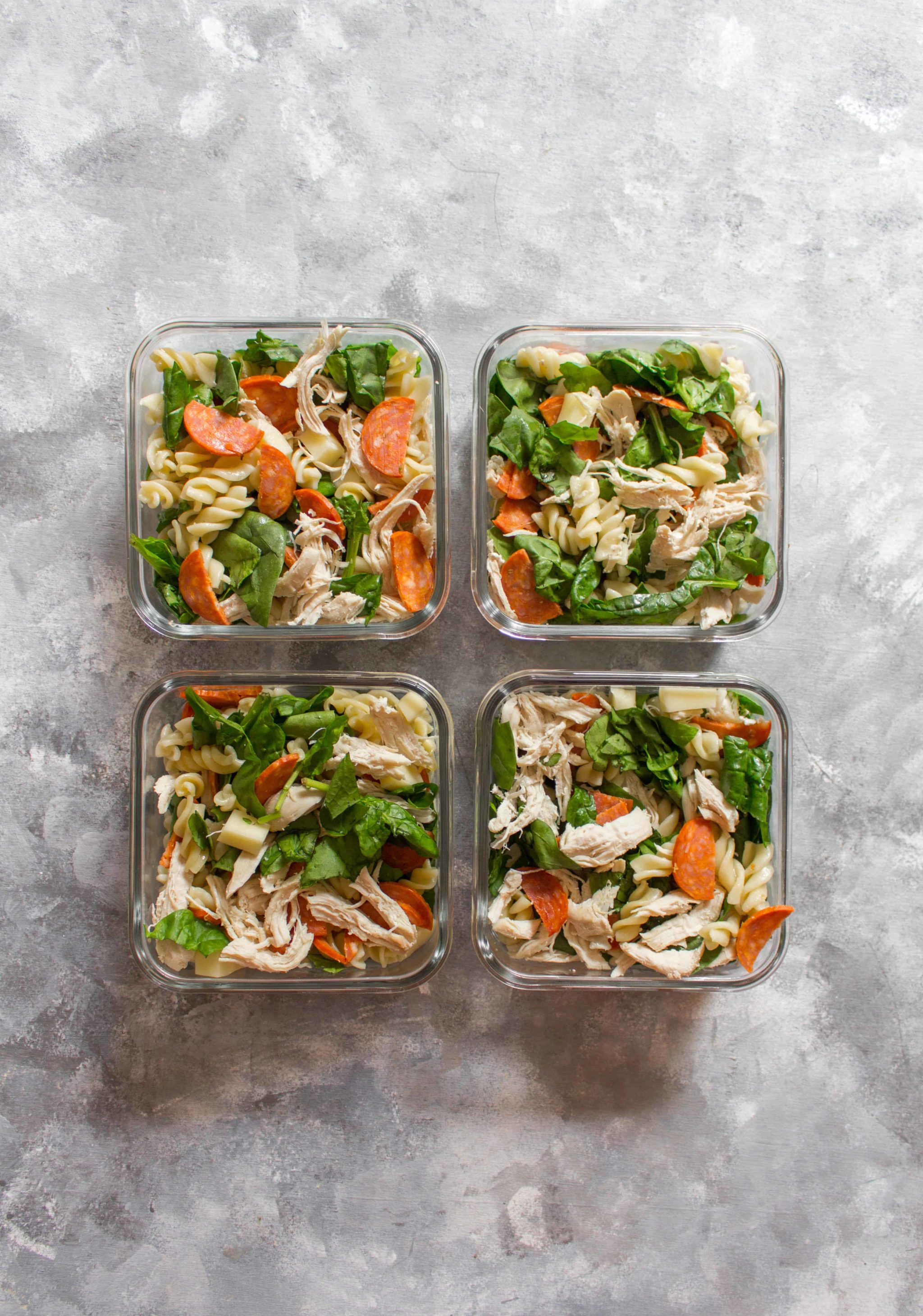 Pasta and veggies in four lunch boxes.