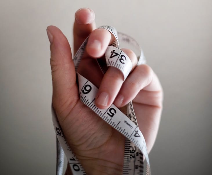 Hand holding measuring tape.