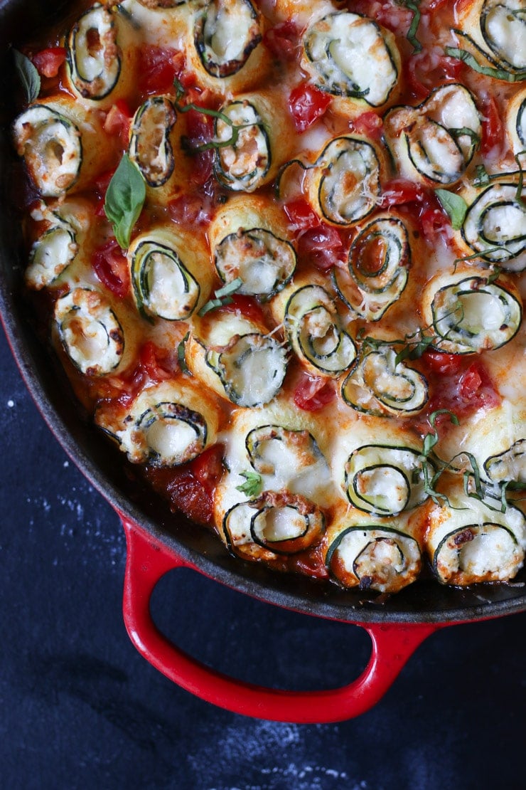 Zucchini lasagna roll ups in a large red skillet. 