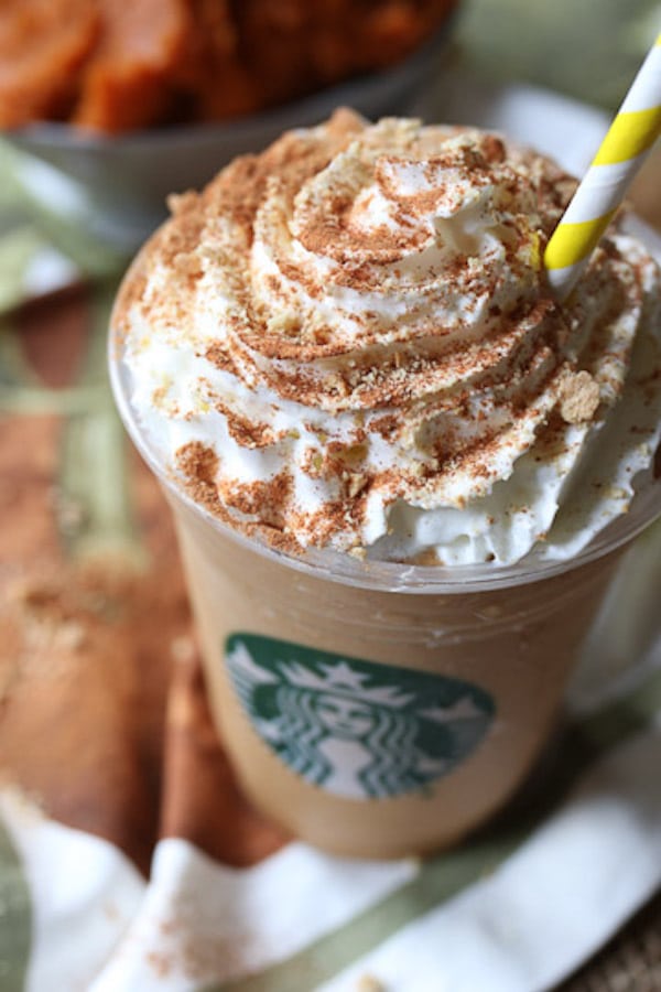 close up of healthy vegan starbucks copycat pumpkin spice frappuccino topped with whipped cream and a straw 