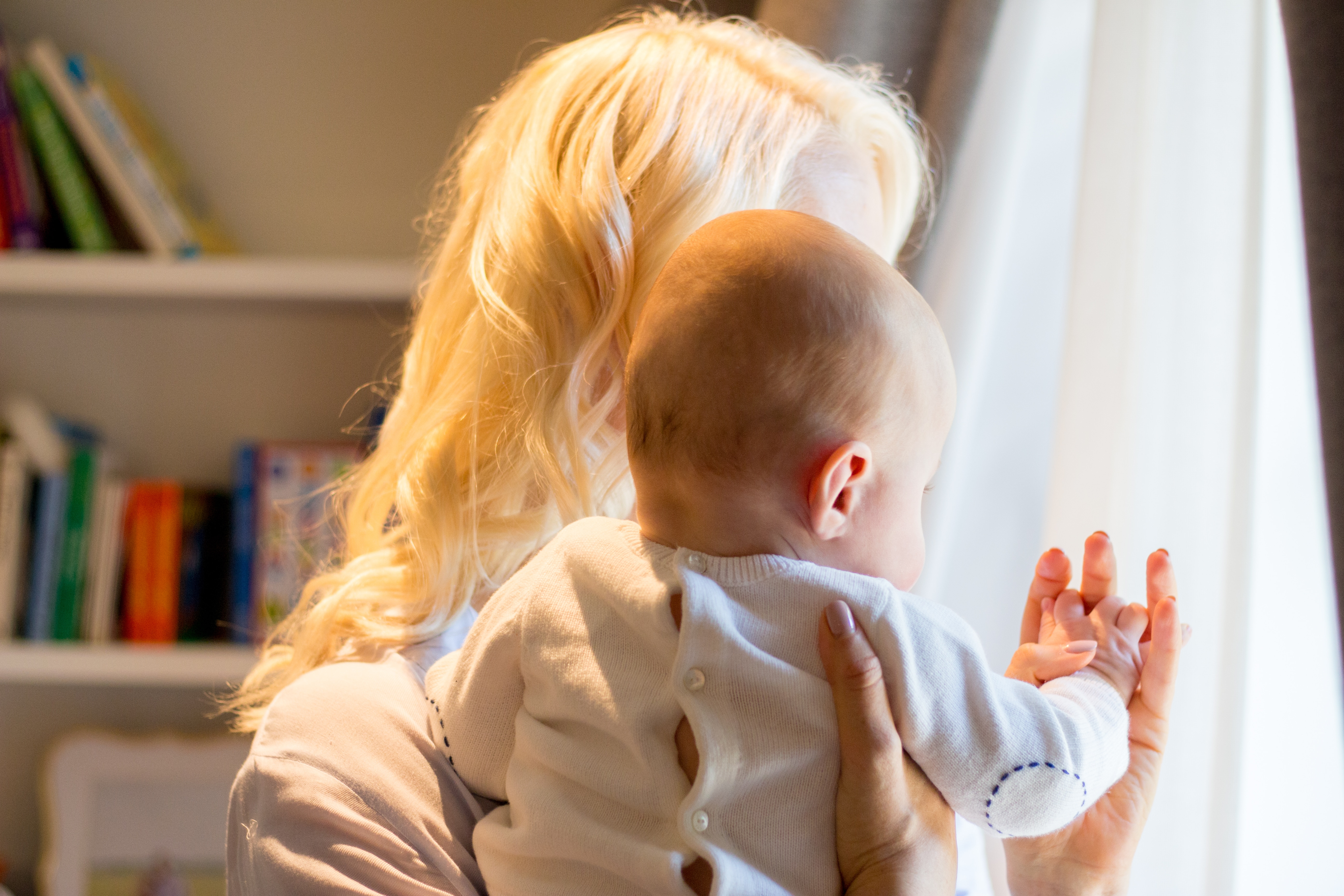 Abbey holding her baby by a window.