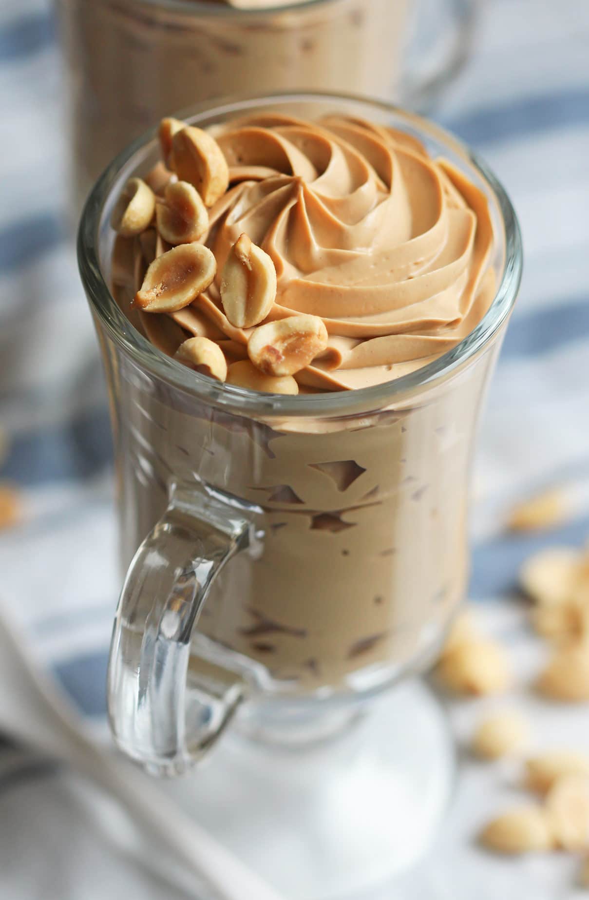 close up of gluten free peanut butter mousse in a clear glass garnished with chopped peanuts