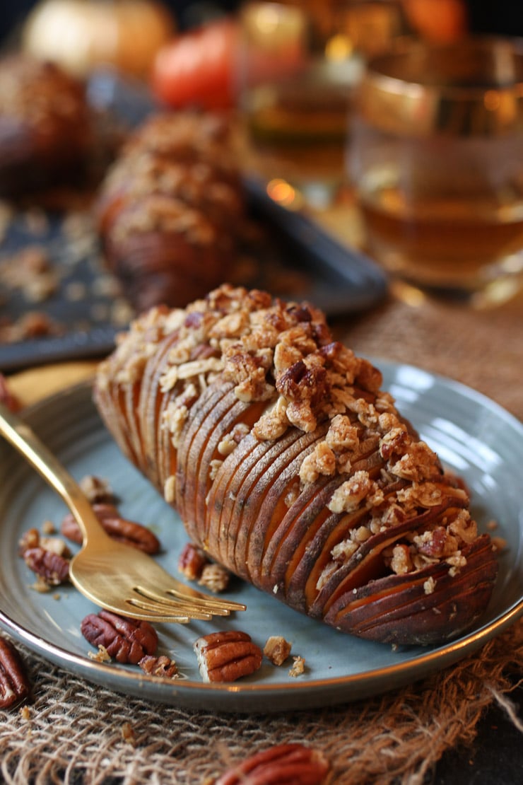 Image of vegan hasselback sweet potatoes with streusel topping on a grey plate with a fork.