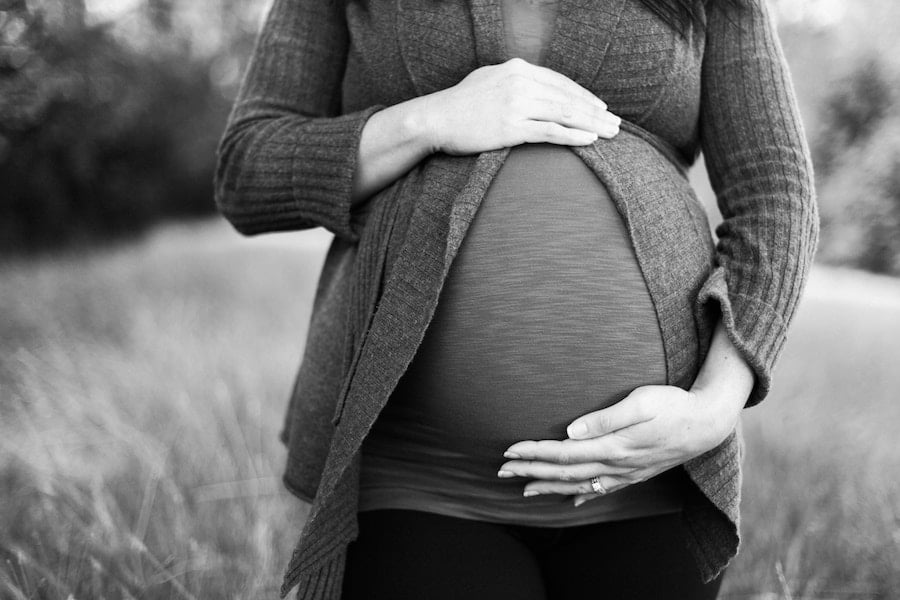 Black and white image of a pregnant person holding their belly.