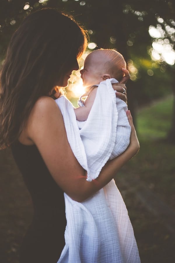 Woman holding her baby outdoors.