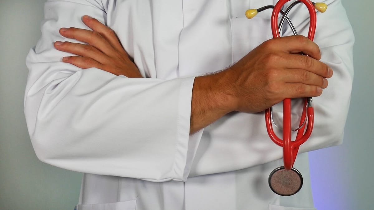 Person in lab coat holding stethescope. 