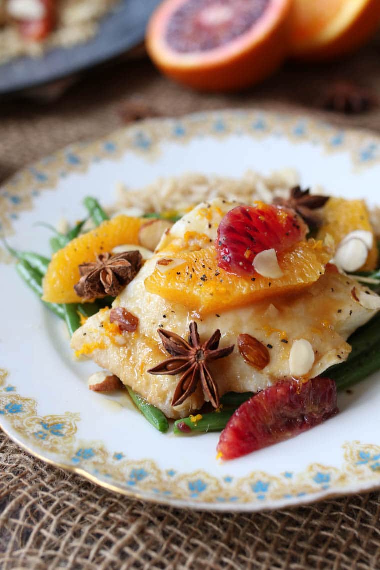 close up of gluten free orange poached halibut served with vegetables on a white plate