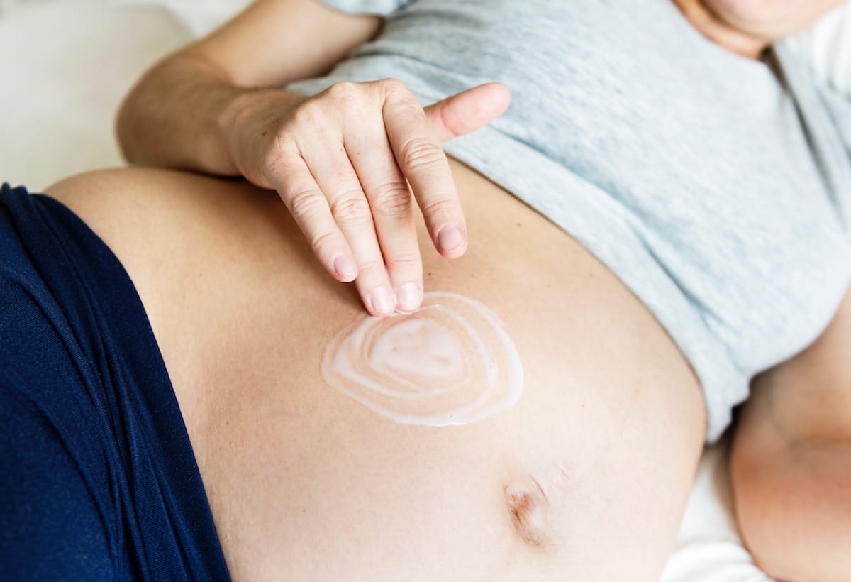 Pregnant person laying on their side touching their stomach.