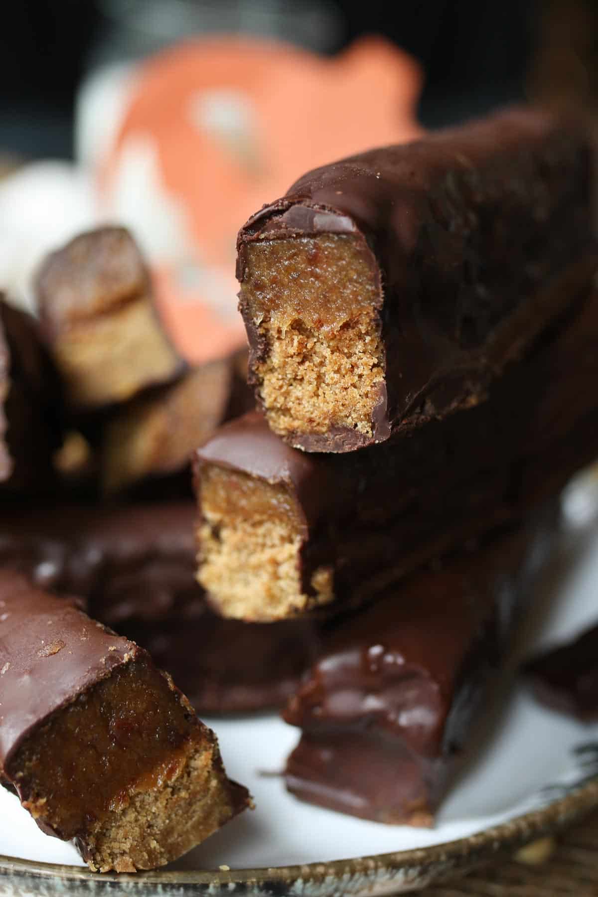 Multiple homemade Twix bars stacked on top of one another on a white plate. 