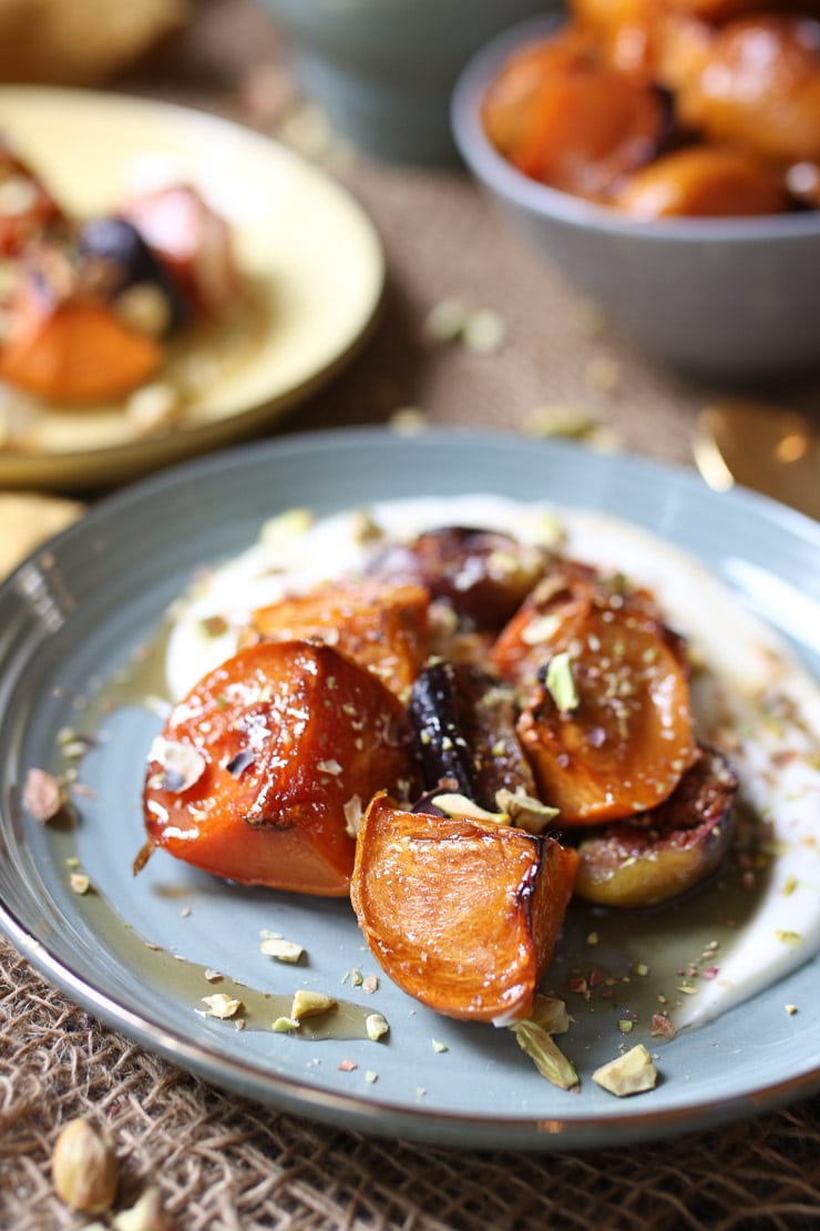 Roasted persimmons and figs on teal plate with crushed nuts.