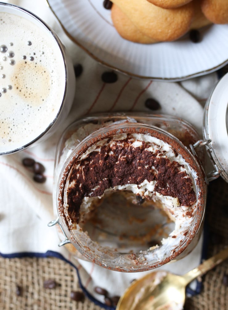 birds eye view of half eaten tiramisu protein oatmeal in a glass jar topped with cocoa powder