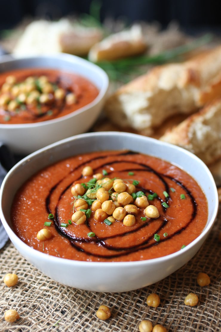 close up of Tomato soup served in a white bowl topped with chickpeas. 