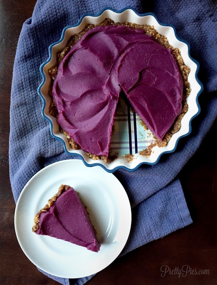 A purple sweet potato lie in a baking dish with one slice cut out onto a plate.