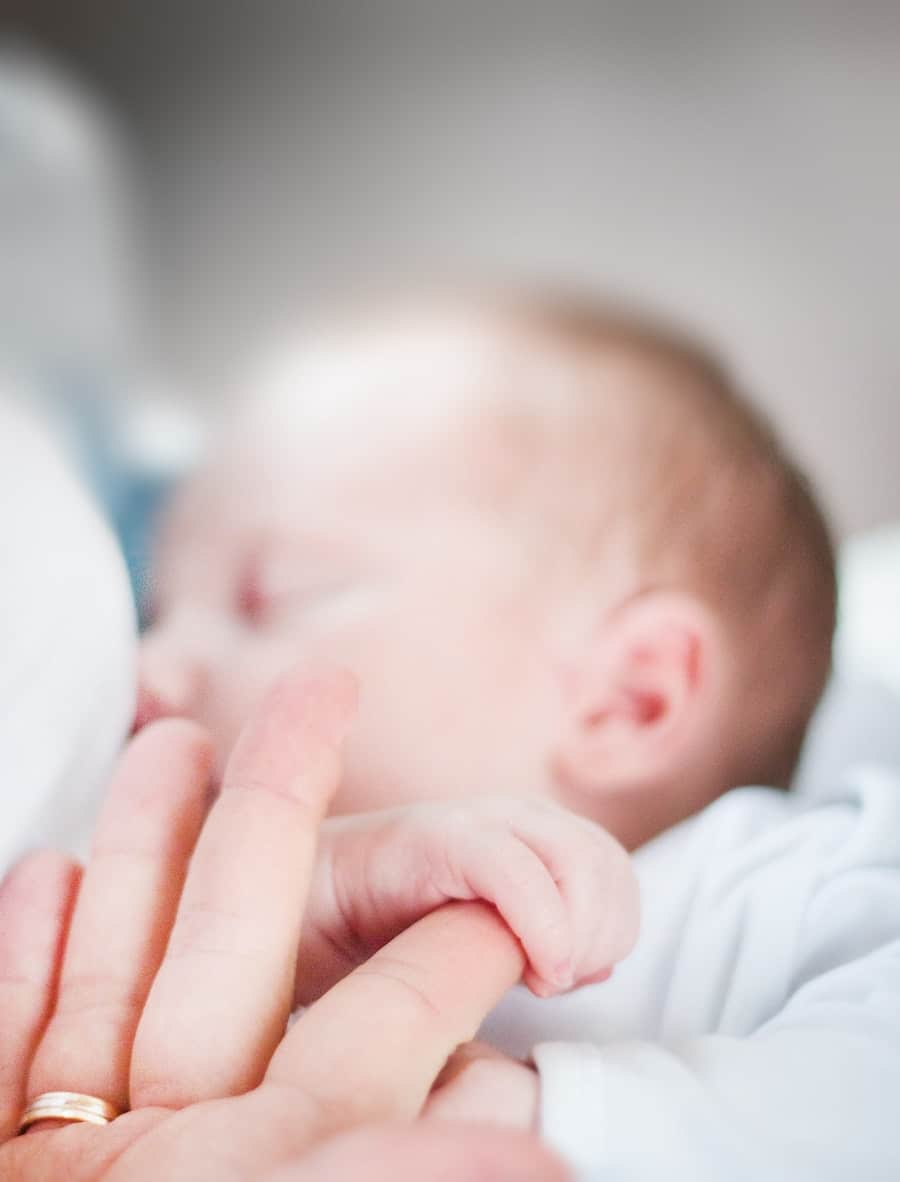 Hand holding a baby's hand.