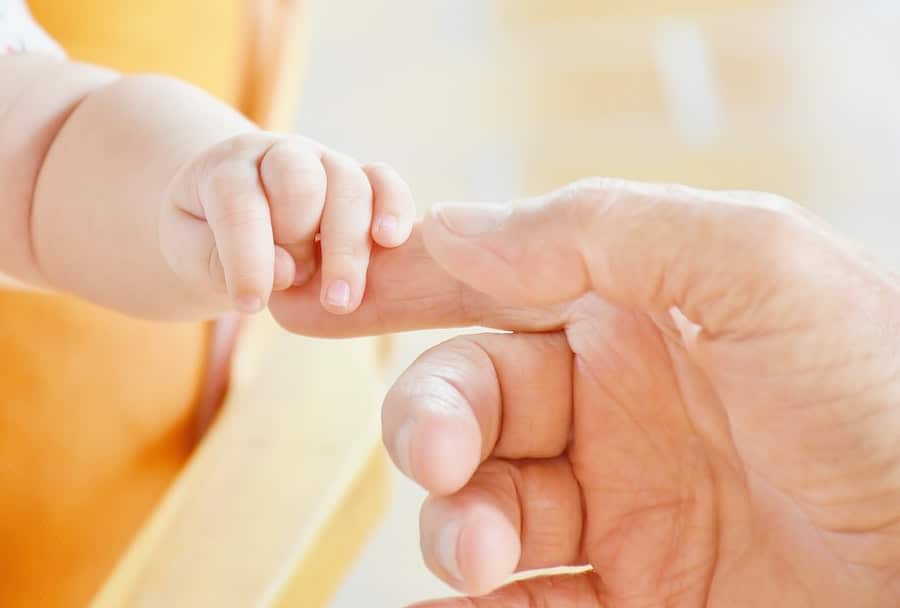 Hand holding baby's hand.