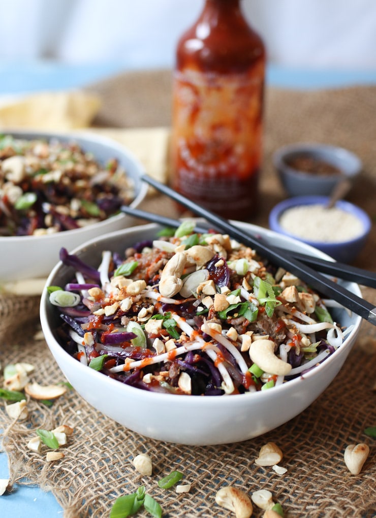 Egg roll in a bowl dinner recipe in a white and grey bowl served with chopsticks and hot sauce.