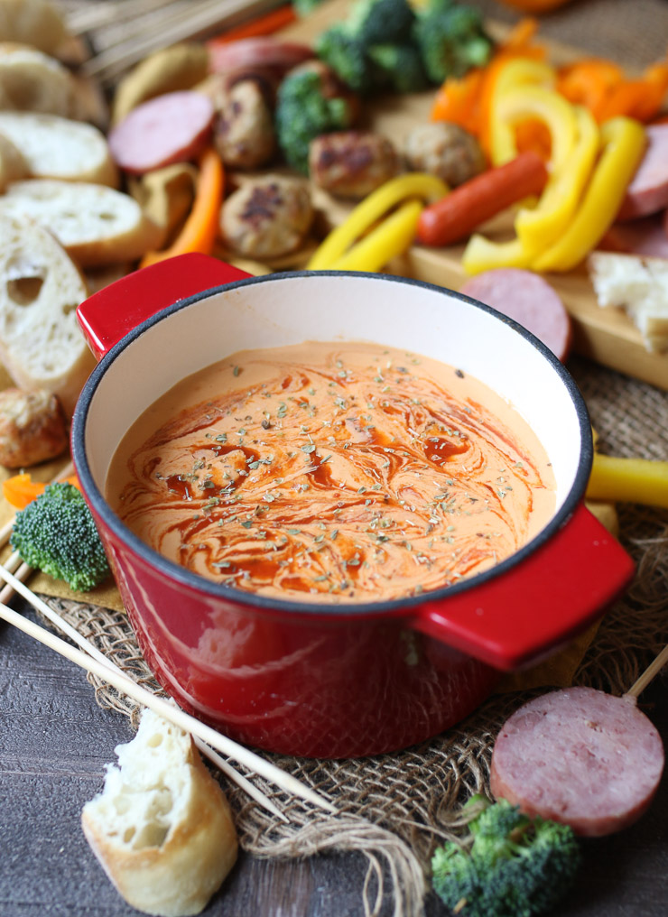 image of keto pizza fondue in a large red pot garnished with herbs