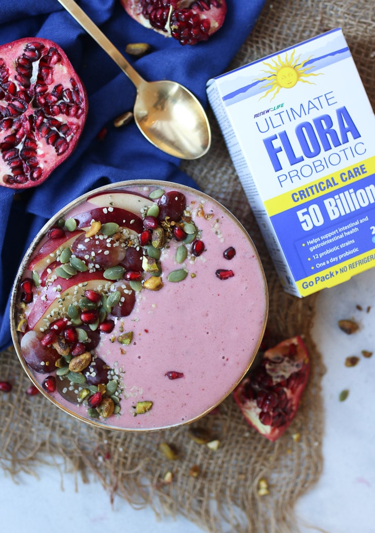 birds eye view of a pink smoothie bowl next to a box of probiotic supplements 