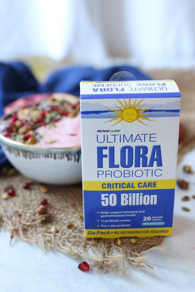 close up of probiotic supplements with smoothie bowl in the background