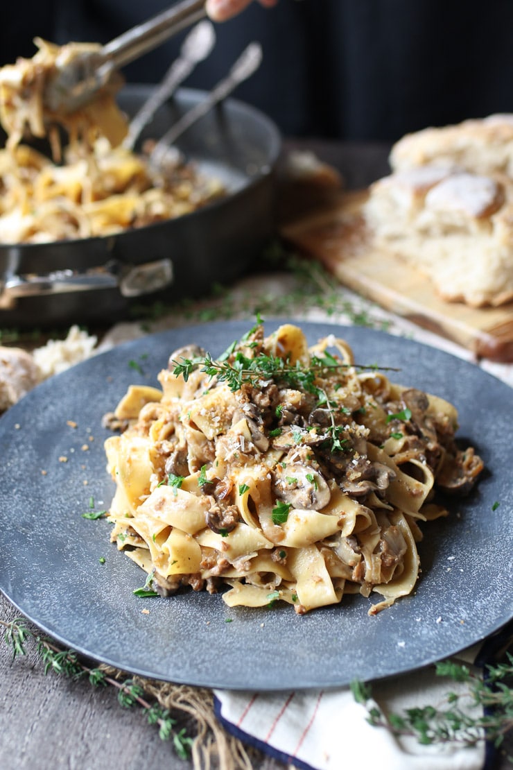 Vegan mushroom pasta on a grey plate garnished with fresh herbs.