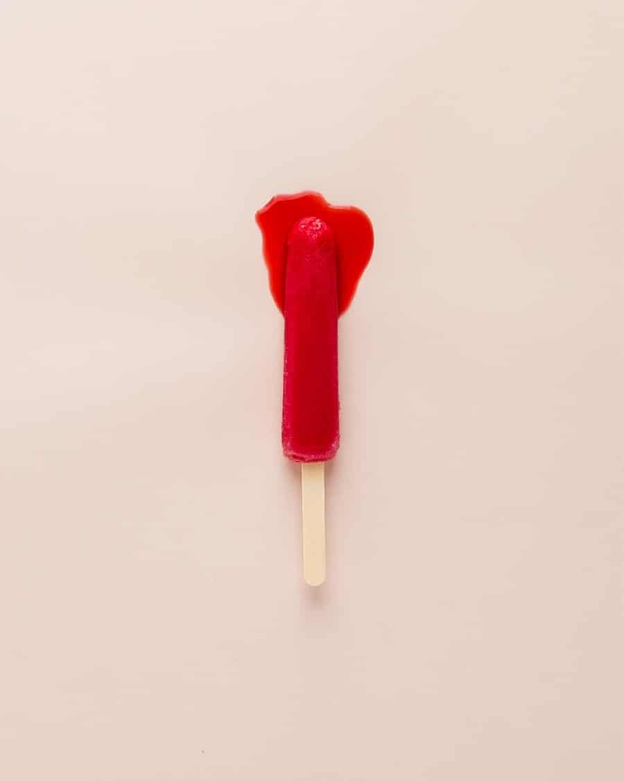 Red melting popsicle against a light pink background.