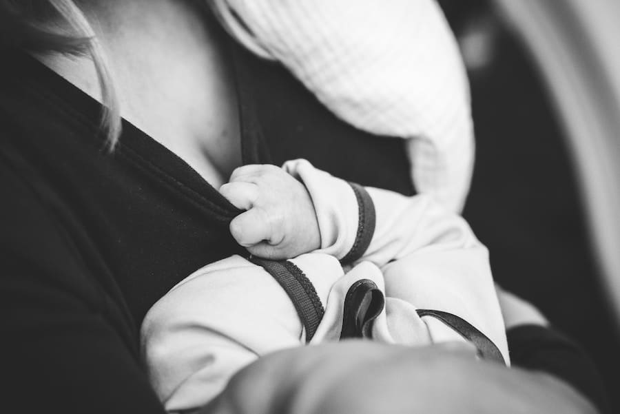 Black and white image of a person holding a baby.