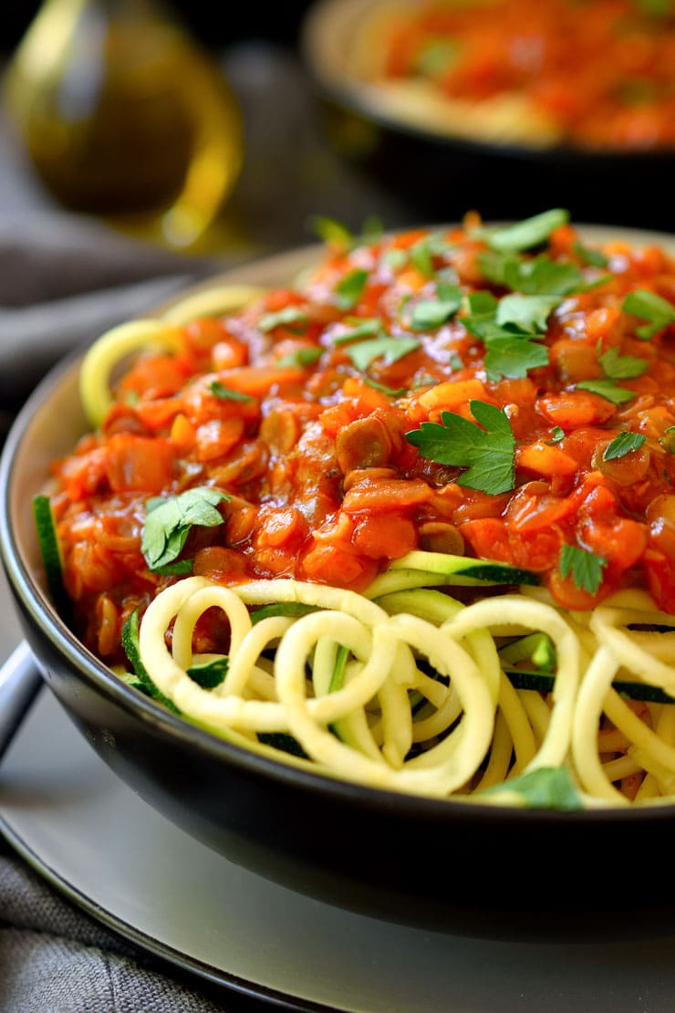 A black bowl with lentil bolognese with zucchini pasta.