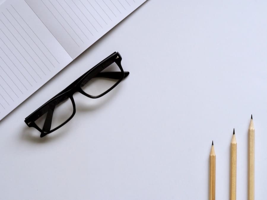 white desk with pencils, glasses, and a book