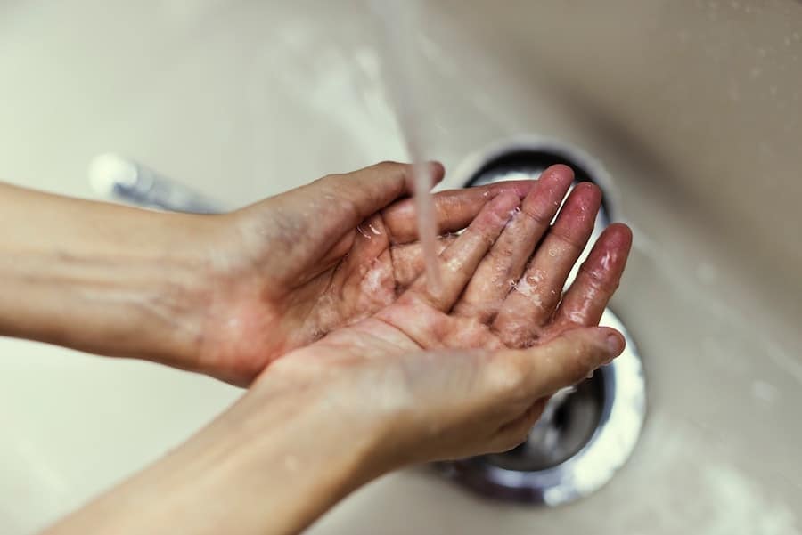 Person washing their hands discussing allergy prevention tips.