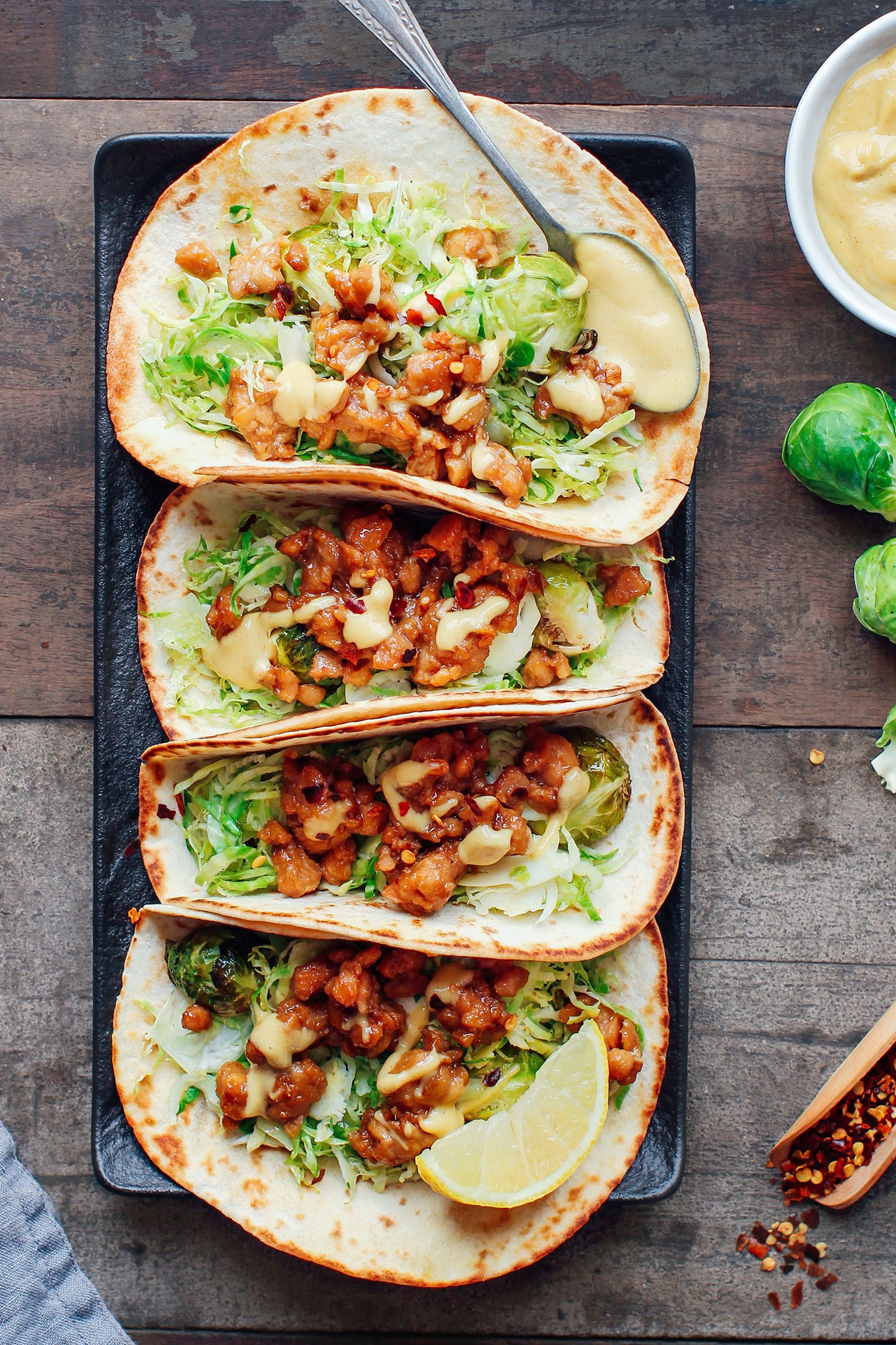 A birds eye view of four tempeh scramble and roasted brussels sprouts tacos. 