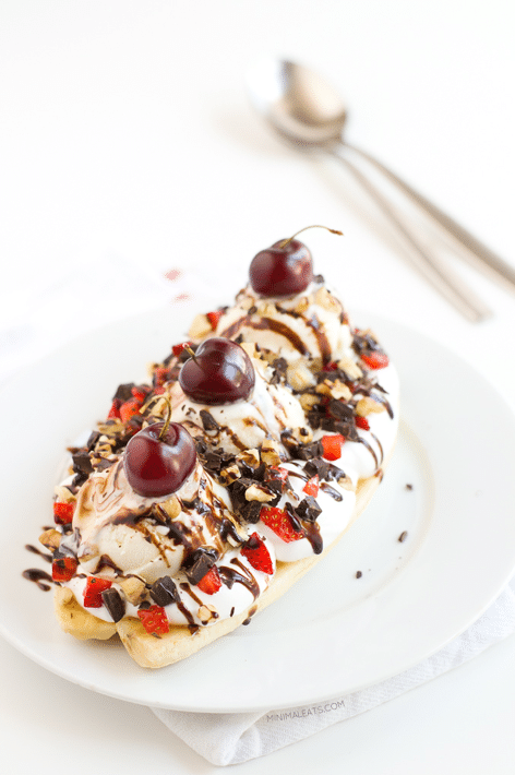 vegan banana split on a white plate garnished with fresh fruit and chocolate