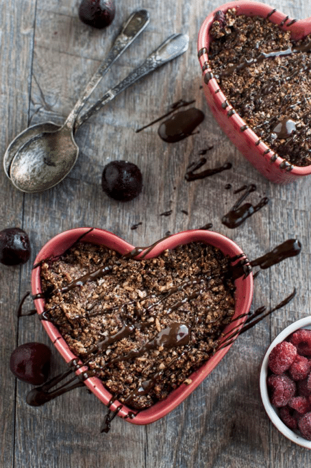 birds eye view of heart shaped pink bowl containing vegan chocolate and fruit crisp