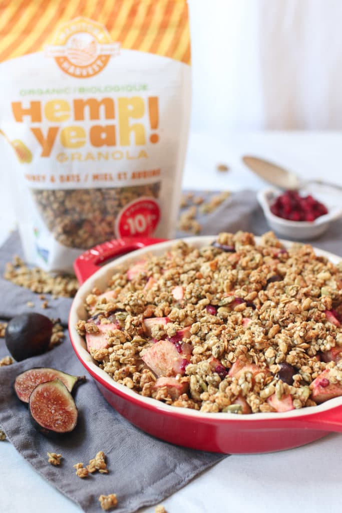 Granola fruit crisp in a red casserole dish with a bag of granola in the background.