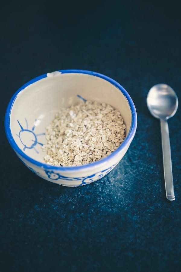 oats in a small bowl next to a silver spoon