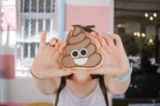 Person holding up a cookie shaped like a poop emoji.