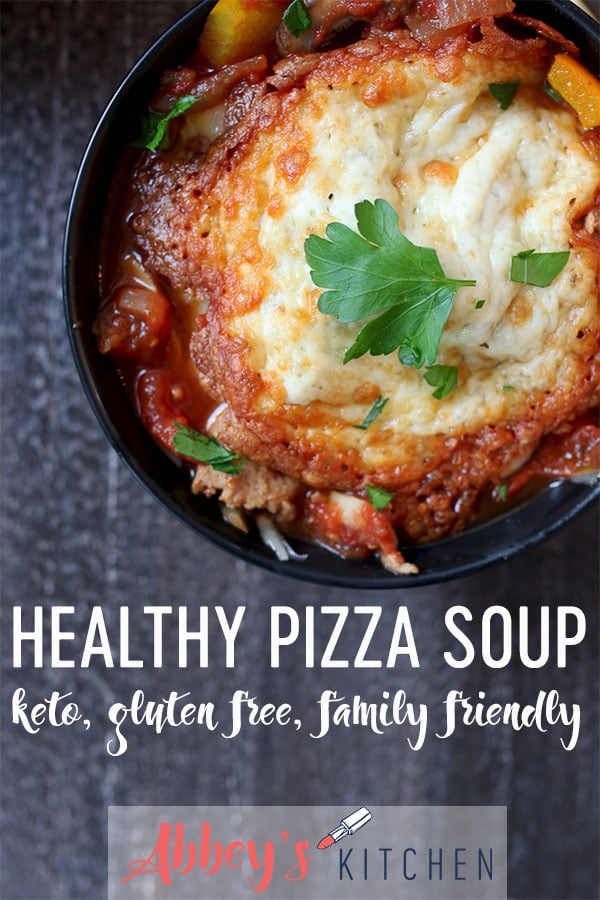 Close up of keto pizza soup in a black bowl topped with melted cheese and parsley garnish.
