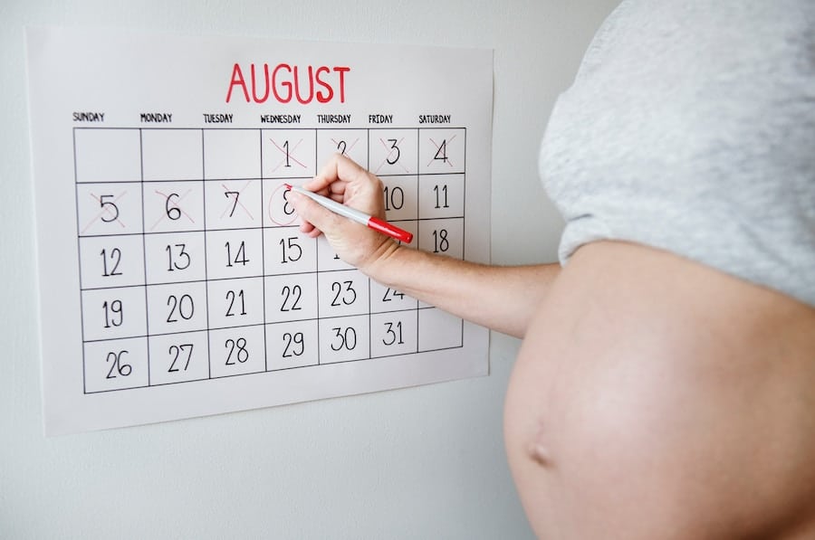 Pregnant women marking due date on a calendar.