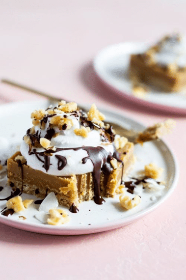 close up of vegan salted peanut butter crunch torte on a white plate garnished with nuts and chocolate