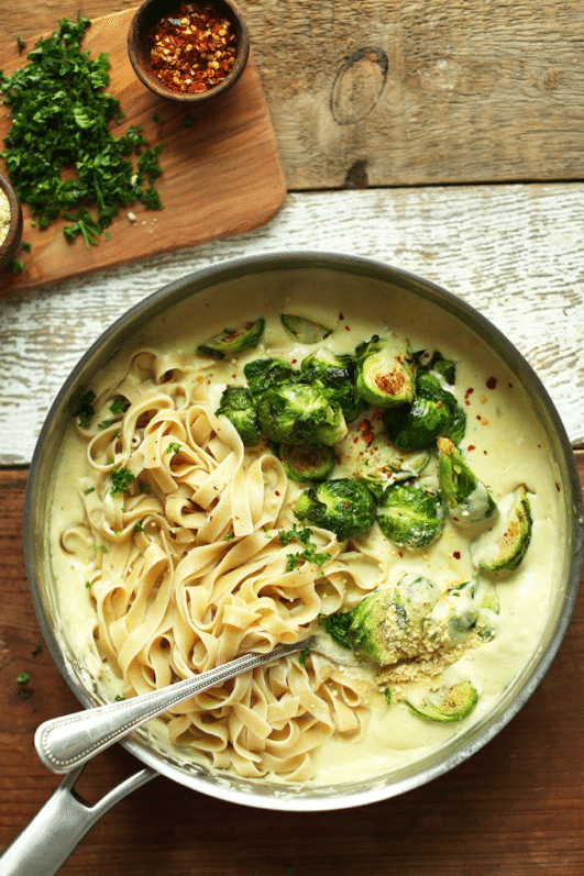 birds eye view of garlic and white wine pasta garnished with brussels sprouts in a large bowl