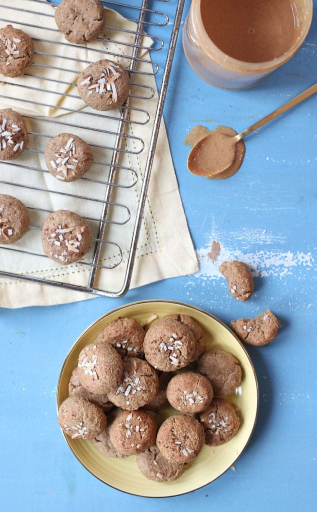 Chickpea peanut butter baby biscuits on a yellow plate next to a rack of biscuits.