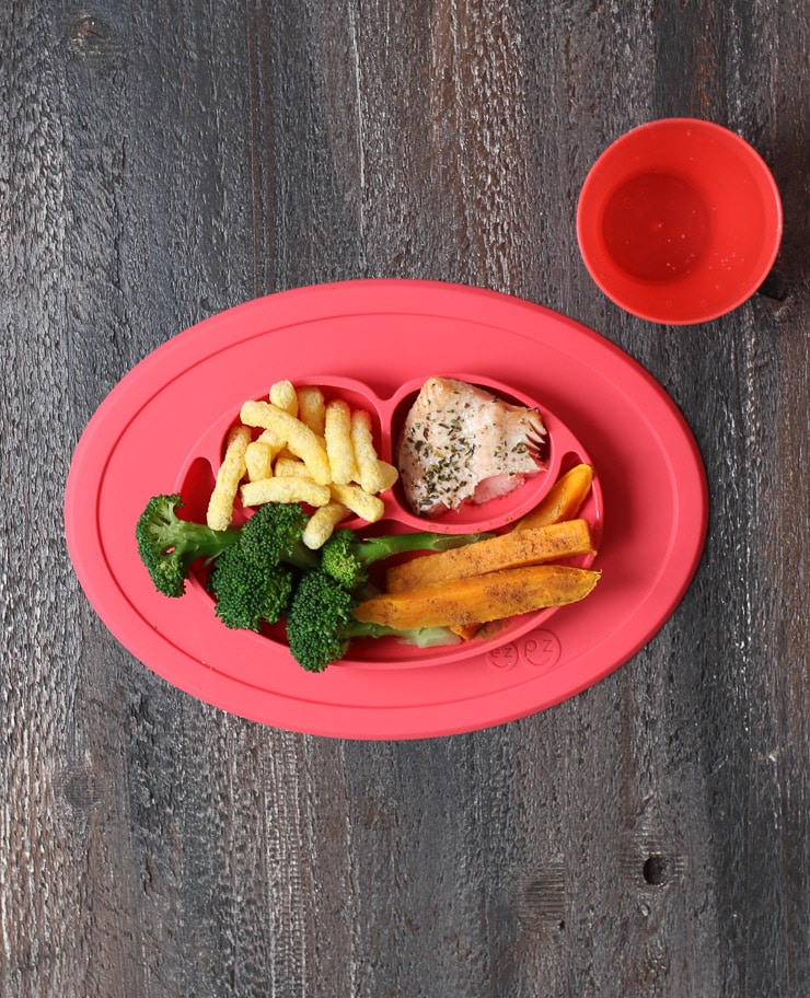 Baby led weaning lunch on a red plate containing broccoli, sweet potato, salmon and baby gourmet carrot sticks.