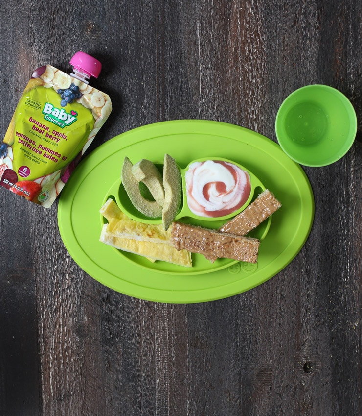 Baby led weaning breakfast containing strips of avocado, omelette, toast and yogurt. 